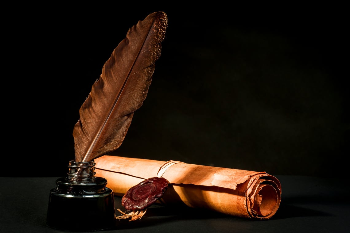 A parchment scroll with a quill in a inkwell on a black background